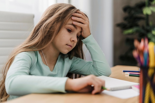 Chica tiene dolor de cabeza mientras hace clases en línea