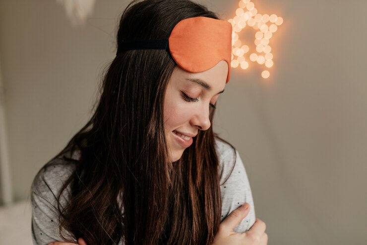 Chica tímida romántica con cabello oscuro con máscara para dormir en la cabeza apoyada en casa. Mañana despierta en casa