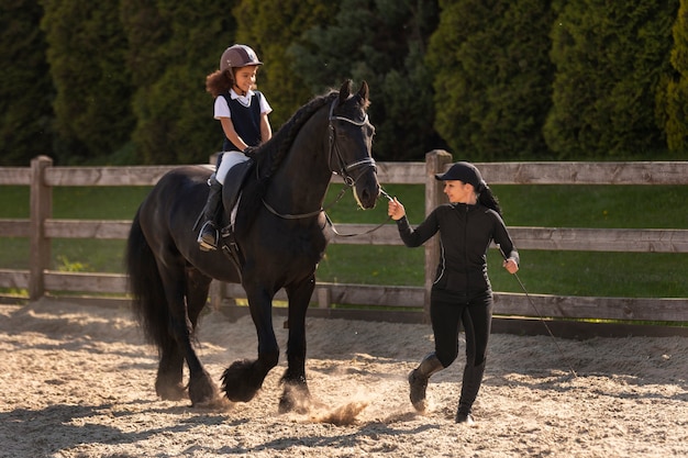 Foto gratuita chica de tiro completo aprendiendo a montar a caballo.