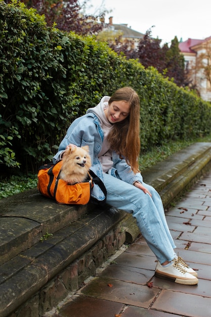 Chica de tiro completo con cachorro en bolsa