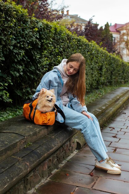 Chica de tiro completo con cachorro en bolsa