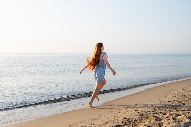 Chica de tiro completo caminando en la playa