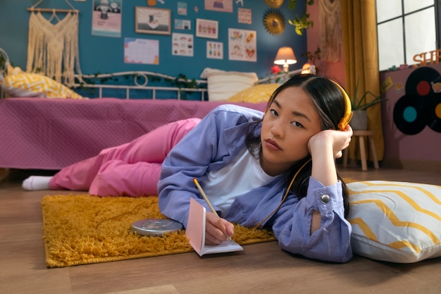 Foto gratuita chica de tiro completo escribiendo en cuaderno en el piso