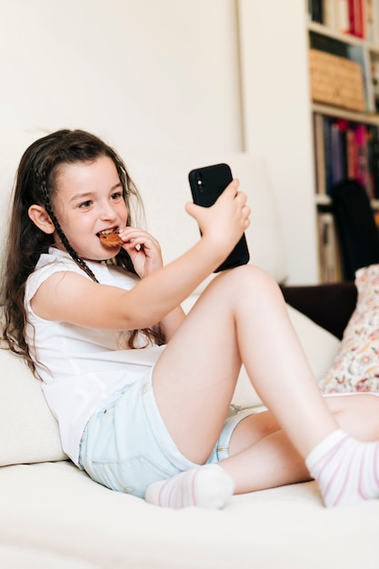 Chica de tiro completo con galleta tomando una selfie