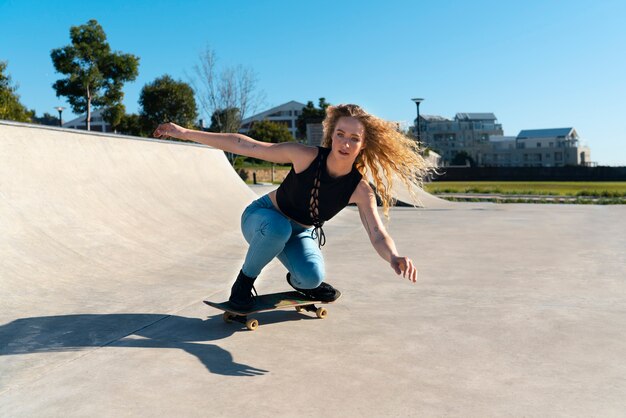 Chica de tiro completo haciendo truco en patineta