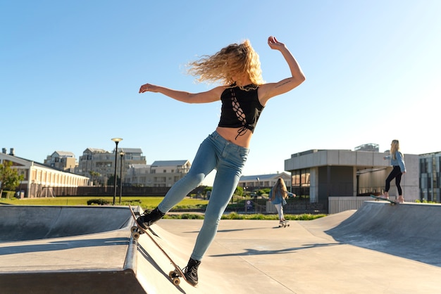 Chica de tiro completo haciendo trucos en patineta