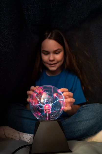 Chica de tiro completo interactuando con una bola de plasma