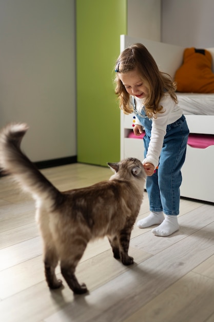 Chica de tiro completo jugando con gato