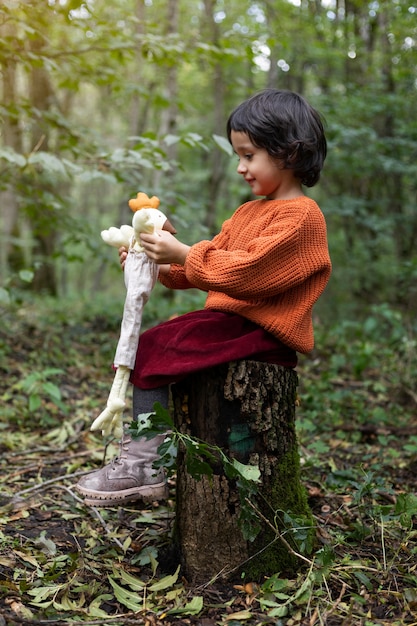 Chica de tiro completo jugando con juguetes en la naturaleza