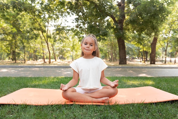 Chica de tiro completo meditando fuera