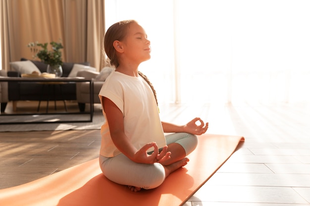 Chica de tiro completo meditando sobre estera de yoga