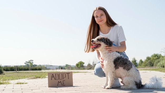 Foto gratuita chica de tiro completo con perro y adoptarme signo