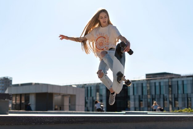 Chica de tiro completo saltando con patineta