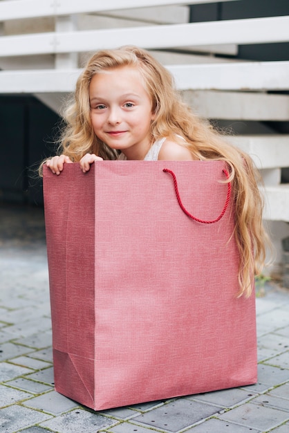 Chica de tiro completo sentada en una bolsa de regalo