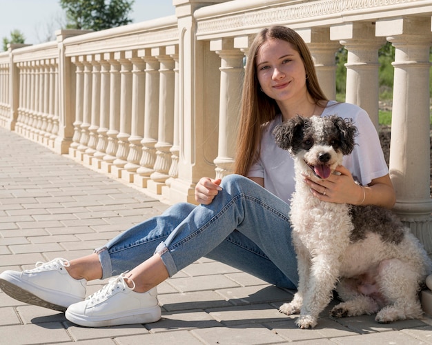 Chica de tiro completo sentada con lindo perro