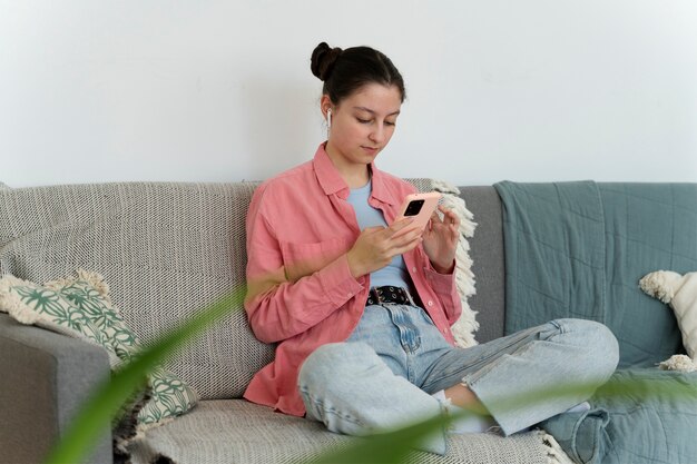 Chica de tiro completo en el sofá con teléfono inteligente