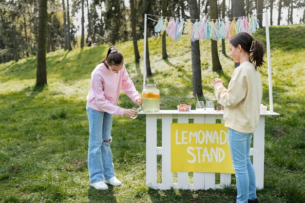 Chica de tiro completo vendiendo limonada fresca