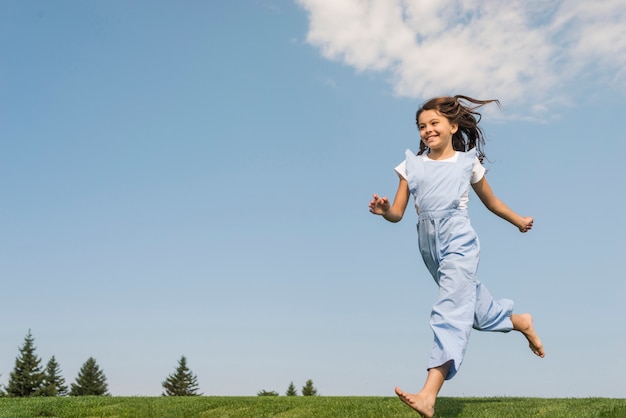 Foto gratuita chica de tiro largo corriendo descalzo sobre hierba