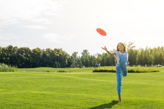 Chica de tiro largo jugando con frisbee