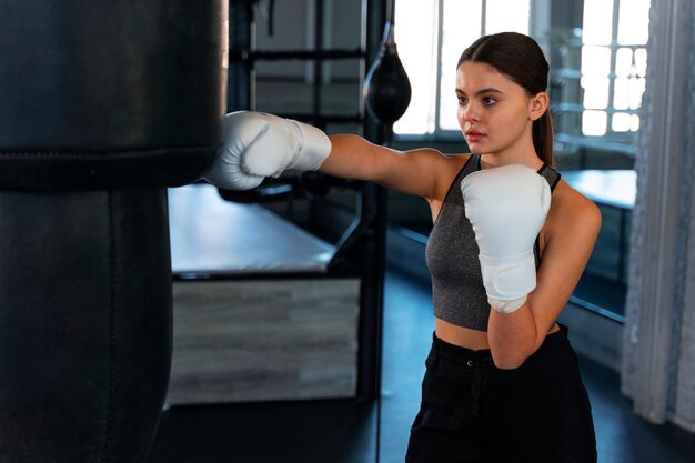 Chica de tiro medio aprendiendo boxeo