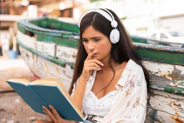 Chica de tiro medio con auriculares leyendo