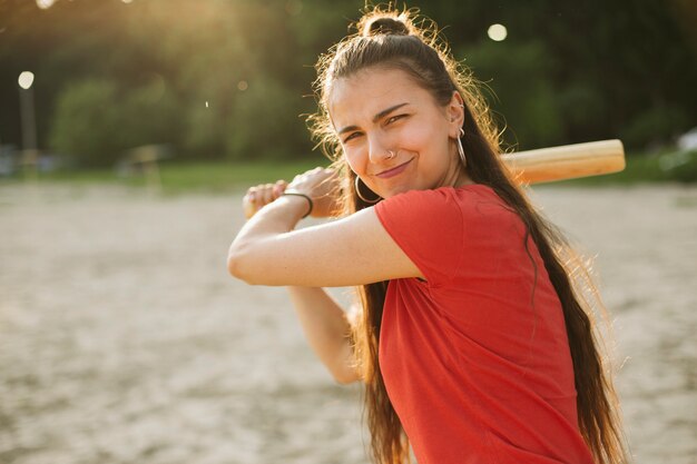 Chica de tiro medio con bate de béisbol posando