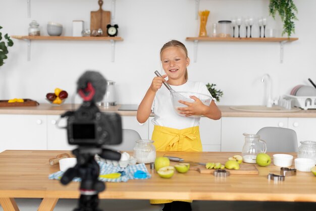 Chica de tiro medio cocinando en cámara