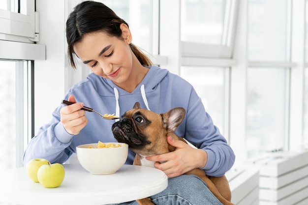 Chica de tiro medio comiendo con perro