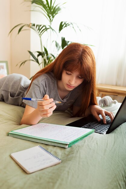 Chica de tiro medio estudiando con portátil