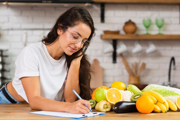 Chica de tiro medio con gafas escribiendo algo