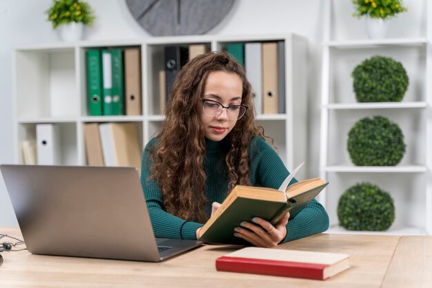 Chica de tiro medio con gafas estudiando en interiores