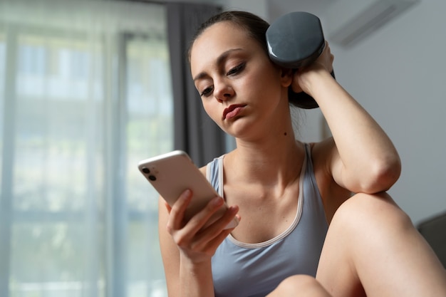 Chica de tiro medio haciendo ejercicio con teléfono inteligente