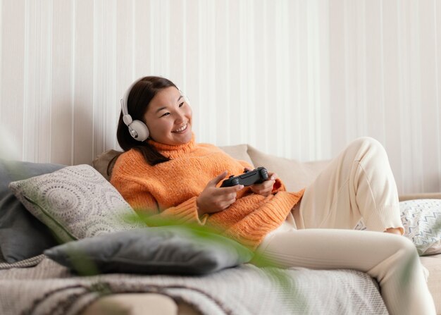 Chica de tiro medio jugando videojuegos en el sofá