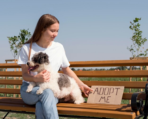 Chica de tiro medio con lindo perro en un banco