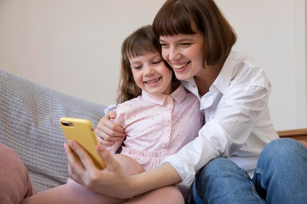 Chica de tiro medio y madre tomando selfies