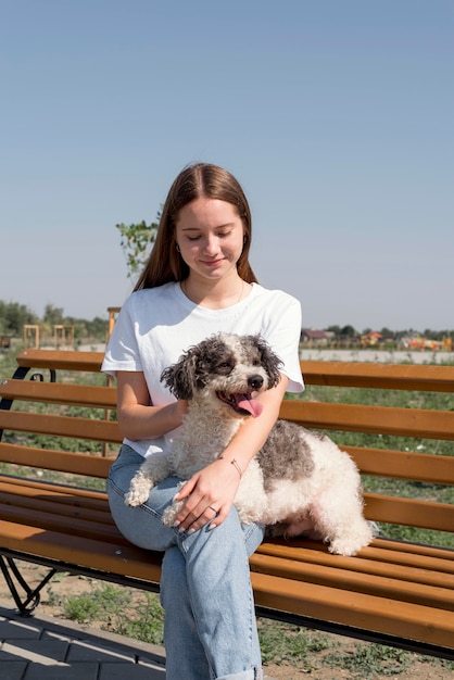 Chica de tiro medio con perro en un banco