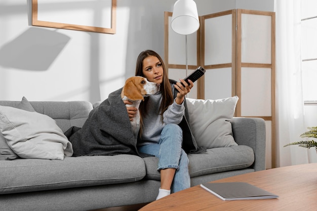 Chica de tiro medio y perro debajo de una manta