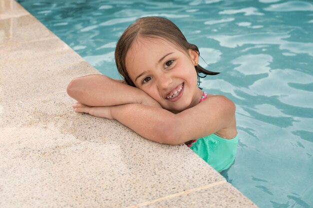 Chica de tiro medio posando en la piscina