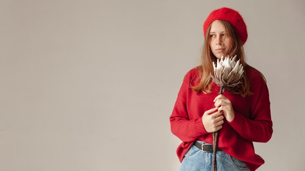 Chica de tiro medio con sombrero rojo y flor posando