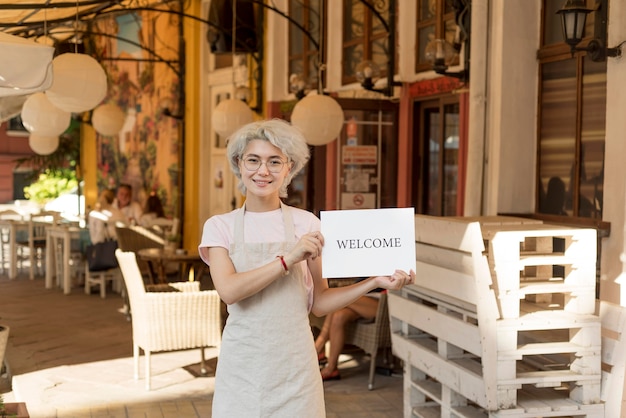 Chica de tiro medio sosteniendo un cartel de bienvenida