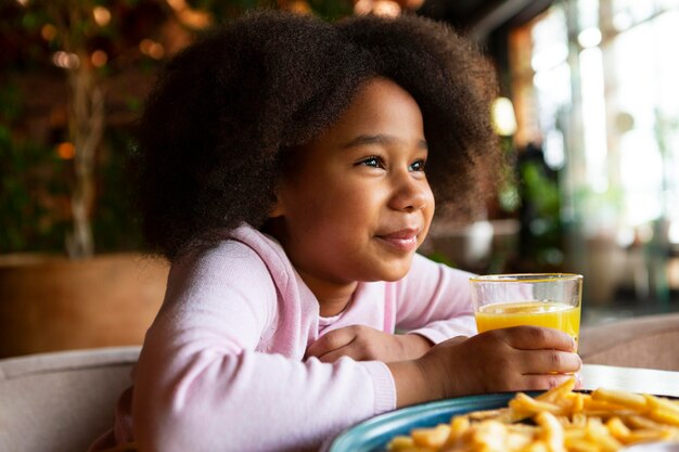 Chica de tiro medio sosteniendo un vaso con jugo