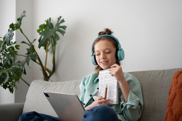 Chica de tiro medio con tableta y auriculares.