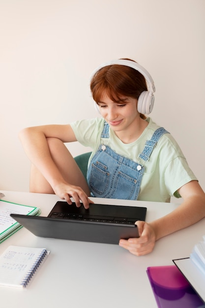 Chica de tiro medio usando audífonos en casa