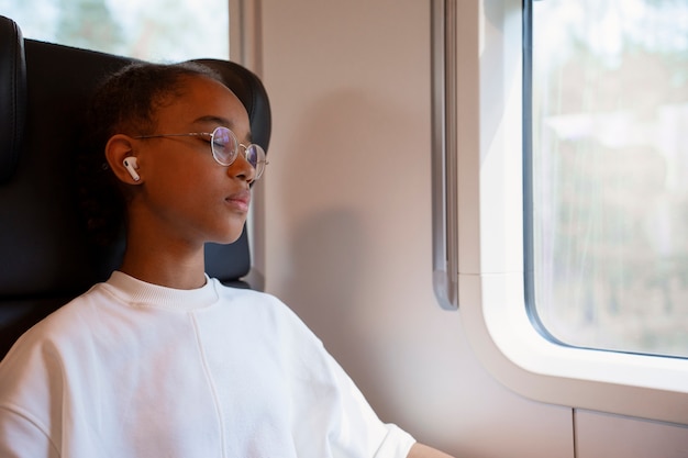 Chica de tiro medio viajando en tren.