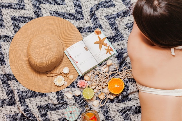 Chica en una toalla de playa con agenda y sombrero 