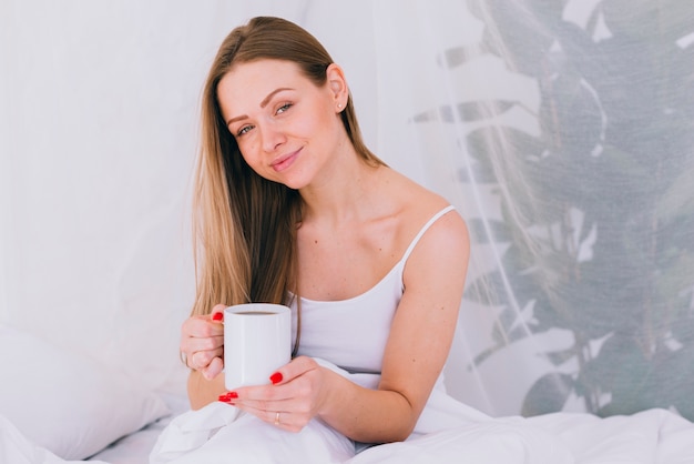 Chica tomando café en la cama