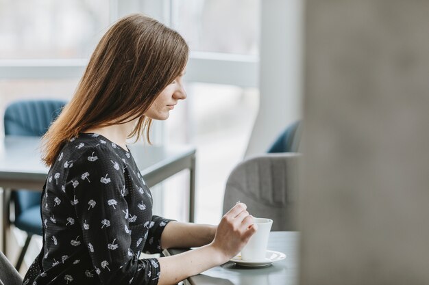 Chica tomando café en un restaurante