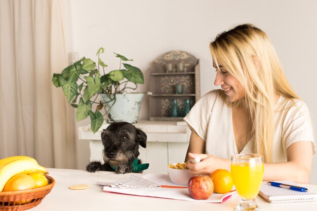 Chica tomando desayuno saludable con perro