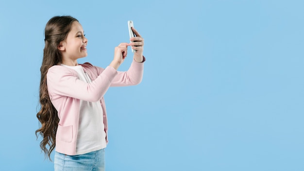 Chica tomando una foto con el teléfono en el estudio