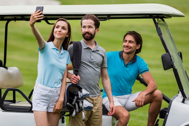 Foto gratuita chica tomando selfie con amigos en el campo de golf